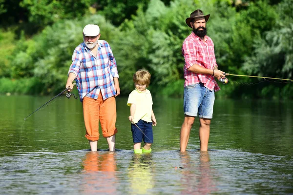 Uomo anziano pesca con figlio e nipote. Weekend estivo. Buon nonno e nipote stanno pescando sul fiume . — Foto Stock