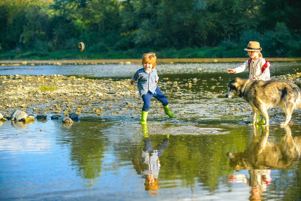 Rivière pierreuse. Petit garçon et petite fille jouant dans la rivière. Les enfants jettent des pierres. Les enfants jouent dans l'eau à la rivière de montagne. Amusant extérieur. Loisirs actifs avec les enfants . — Photo