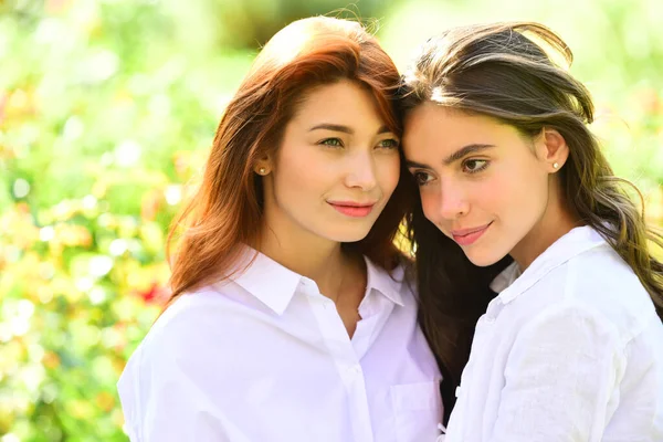 Um casal de raparigas a passar tempo lá fora juntos. Mulheres felizes em um parque no fundo de primavera verde . — Fotografia de Stock