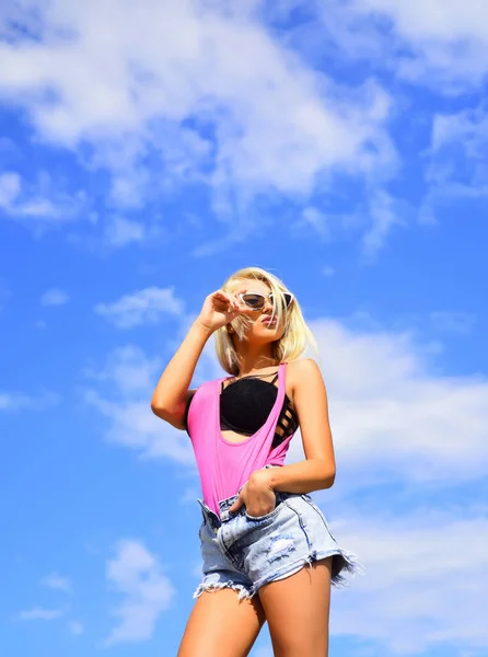 Fashion woman posing over blue sky. Beautiful girl posing on sky background in the hot sun, outdoor portrait. Young blonde beauty woman. — Stock Photo, Image