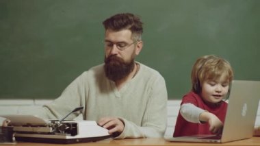 Yaşlılar gençlere karşı. Baba ve oğul. Nesil çatışması. Gençler yaşlılara karşı. Evde eski daktilo ve dizüstü bilgisayarda yazan baba ve oğul..