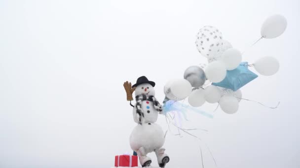 Hombre de nieve divertido al aire libre. Feliz muñeco de nieve divertido celebrar globos sobre fondo de nieve blanca. El muñeco de nieve lleva un sombrero de piel y bufanda para celebrar la Navidad y el Año Nuevo . — Vídeos de Stock