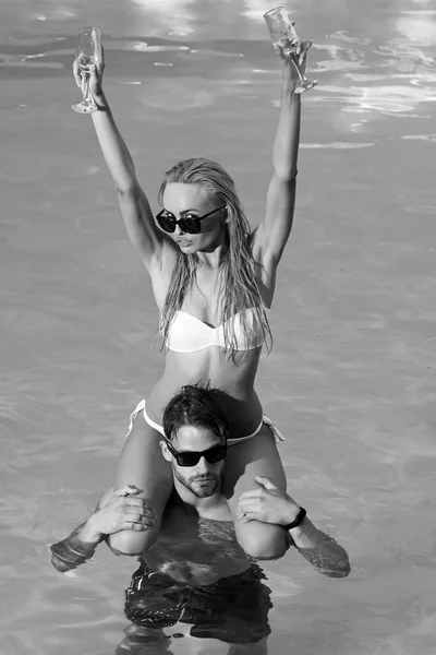 Gelukkig jong romantisch paar in liefde hebben plezier op prachtige strand op prachtige zomerdag. Jong liefdevolle paar ontspant en drinken wijn in het zwembad. — Stockfoto