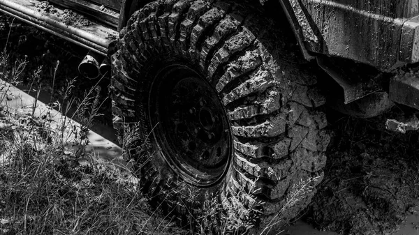 Best Off Road Vehicles. Off-road vehicle goes on the mountain. Bottom view to big offroad car wheel on country road and mountains backdrop. Road adventure. Adventure travel. — Stock Photo, Image