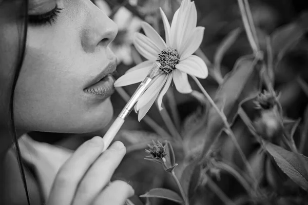 Πρόσωπο καλοκαιρινής γυναίκας. Κοντινό πορτρέτο της νεαρής ελκυστικής γυναίκας που ζωγραφίζει κίτρινα λουλούδια με πινέλο. Λουλούδια ανθίζουν και άνοιξη έννοια κήπο. Όμορφη γυναίκα περπατά στον ανθισμένο κήπο. — Φωτογραφία Αρχείου