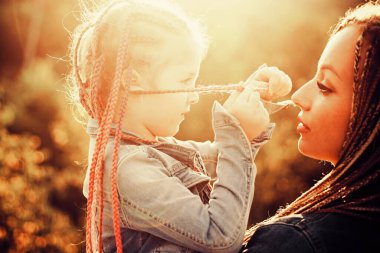 Saç örgüsü modaya uygun. Mutlu ve sevgi dolu bir aile, anne ve kız. Saç örüyorum. Örgü ören güzel bir kız çocuğu..