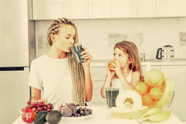 Mãe e filha bebendo matcha de vidro em casa. Suplementos alimentares. e espirulina. A mãe com a filha a tomar o pequeno-almoço na cozinha. Espirulina. Estilo de vida saudável . — Fotografia de Stock