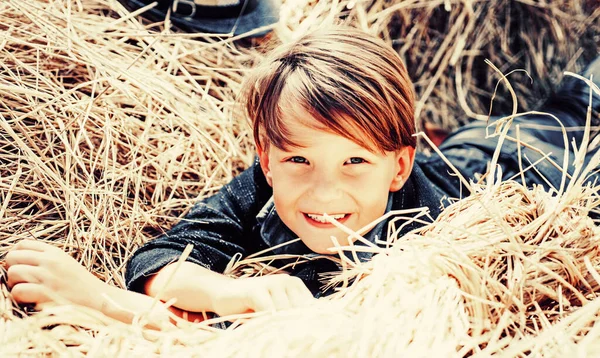 Kid boy holding gold leaf and lies on the hay. Bye summer - hi autumn. Sale for entire autumn collection, incredible discounts and wonderful choice. Kid on an autumn holiday in the farm. — Stock Photo, Image