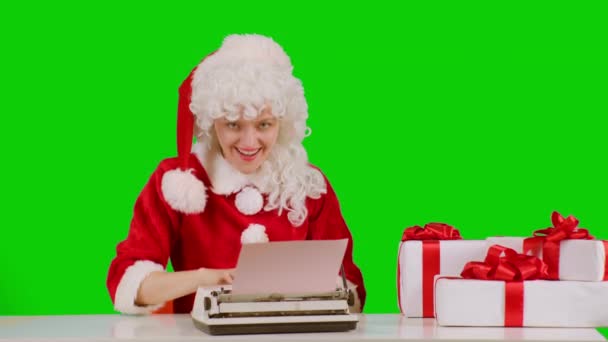 Funny Christmas woman writing letter on typewriter, isolated on green. Many garlands. Christmas , winter holidays and people concept. Letter to Santa Claus. Girl writes her wish. Happy woman writing — Stock Video