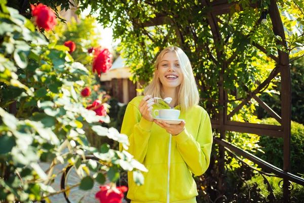 Осенняя женщина в свитере с чашкой кофе улыбается и наслаждается солнцем. Счастливая улыбающаяся девушка с горячим напитком в руках. Счастье в сезон . — стоковое фото