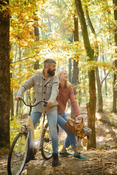 Couple amoureux assis à vélo à la forêt automnale. Pull ensoleillé météo et bonnes vibrations. Les amateurs de vélo au parc d'automne à l'automne jaune fond de feuilles. Heureuse épouse et mari . — Photo