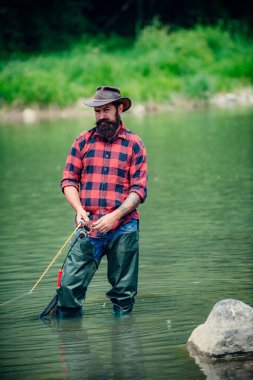 Göl kenarında dinlenen ve balık tutan bir adam. Hafta sonları balık tutmak içindir. Balıkçı erkek hobisi. Usta yemleyici. Sakin ol ve balık tut. Fishman büyük balığı beklerken nehre örgü ördü. Adam balık tutuyor..