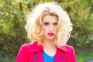 Bahar çiçekleri arka planında şehvetli genç bir kadın. Kıvırcık saçlı, bahar güzeli kız. Bahar makyajı..