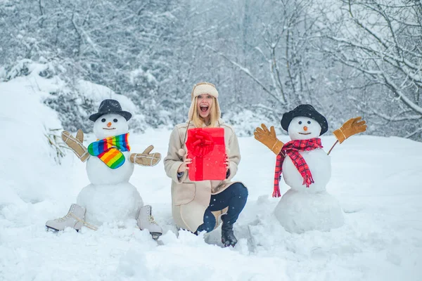 Érzéki téli lány pózol és jól érzi magát. Emberek a hóban. Vidám lány szórakozás hóemberrel a Winter Parkban. Téli időjárás a parkban. — Stock Fotó