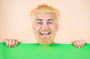 Medya afişi için boş yeşil pano tutan mutlu, heyecanlı adam. Elinde boş bir kağıt parçası tutan bir adam. Kopyalama alanı.