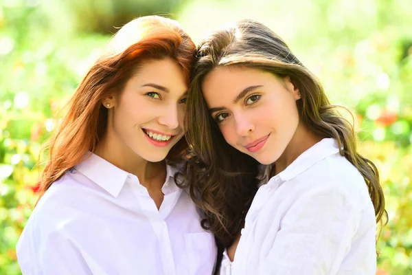 Två glada vackra kvinnor poserar tillsammans medan du tittar på kameran över grön bakgrund. — Stockfoto