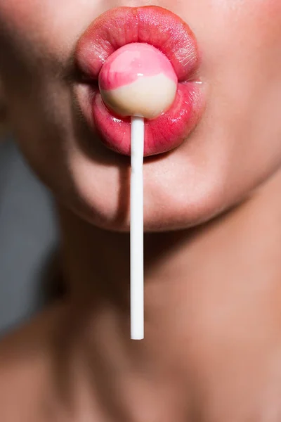 Primer plano de chupar una piruleta. Mujer sexy con labios rojos sosteniendo piruleta, belleza de cerca. Labios sexuales con dulces, dulces sueños sexy. Atractiva hembra boca lame chupa chups, chupa lollipop . — Foto de Stock