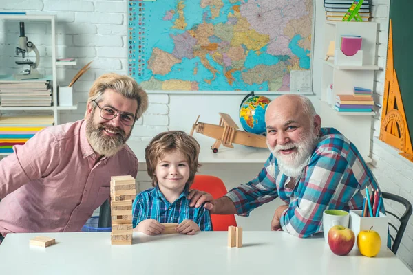 Uomo di età diverse. Allievo ragazzo con padre e nonno. Tre generazioni di uomini attivi che giocano in salotto . — Foto Stock