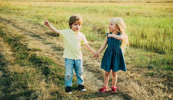 Piccola coppia innamorata di campagna. Amici sorridenti che ridono. Emozioni umane e stile di vita. Ragazzo felice sul campo estivo. infanzia spensierata . — Foto Stock