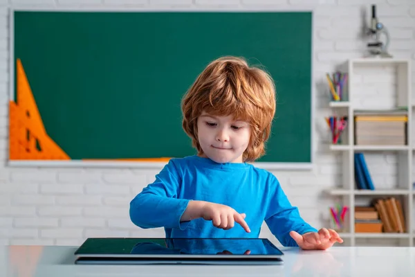 在学校课堂上学习数码平板电脑.学生在课堂上使用数字平板电脑。可爱的学龄前小男孩，在教室里有老师的学习. — 图库照片