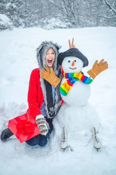 Roztomilá dívka dělá sněhuláka na zasněženém poli venku. Dívka hrající si se sněhulákem v zimním parku. Zimní den. — Stock fotografie