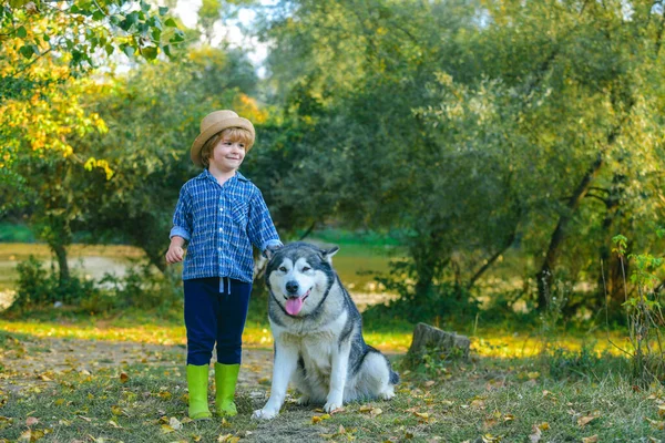 Μικρά παιδιά περπατούν μαζί με το σκυλάκι τους έξω. Λατρεύω τα παιδιά. Το αγοράκι παίζει με το σκύλο του έξω και διασκεδάζει μαζί. Έννοια της παιδικής ηλικίας. — Φωτογραφία Αρχείου