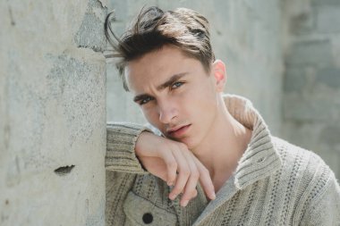 Gri duvara karşı tatmin olmuş genç bir adamın portresi. Gri arkaplandaki modaya uygun Latin adamın yüzünü kapat.