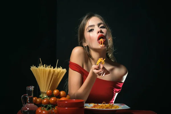 İtalyan tarzı seksi bir kadın elleriyle spagetti yiyor. Seksi bir mutfak. Kadın spagetti ile tabak tutun. Kadın spagetti pişirdi. İtalyan yemeği ve menü konsepti. — Stok fotoğraf