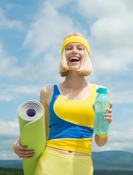 Donna in forma. Tempo di riposo. La ragazza sportiva beve acqua. Foto di modello di fitness muscolare isolato su sfondo cielo. Concetto sanitario . — Foto Stock