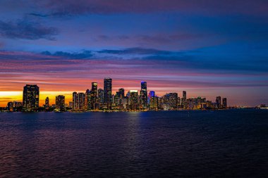 Miami Florida, şehir merkezindeki gökdelen binaları. Miami City, Florida gökdelenleri ve deniz üzerinde yansıması olan bir köprü ile alacakaranlıkta gökyüzü manzarası. Miami İş Bölgesi