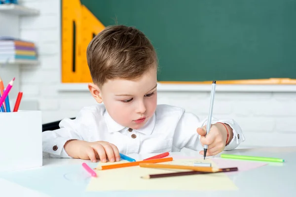 Niño lindo en el aula cerca del escritorio de pizarra. El chico está aprendiendo en clase. Educación preescolar . —  Fotos de Stock