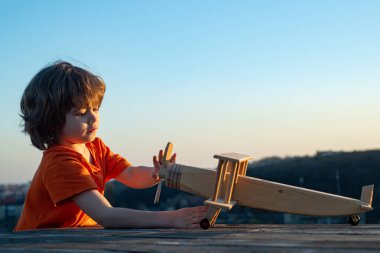 Tahta uçaklı küçük bir çocuk. Çocuk oynuyor ve pilot olmanın hayalini kuruyor. Çocuk rüyaları ve hayal gücü konsepti. Kırsalda çocukluk..