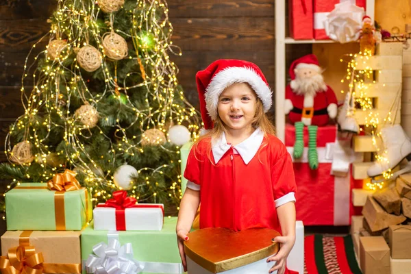 Χαρούμενο χαριτωμένο παιδί που ανοίγει χριστουγεννιάτικο δώρο. Ευτυχισμένο παιδί στολίζει χριστουγεννιάτικο δέντρο. Χαριτωμένο παιδάκι κοντά στο χριστουγεννιάτικο δέντρο. — Φωτογραφία Αρχείου