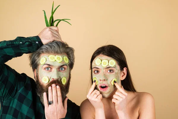 Couple facial à l'aloe vera crème. Soins du visage, beauté et spa. Belle fille et bel homme barbu avec masque facial vert sur fond jaune isolé. Drôle surpris et fou concept comique — Photo