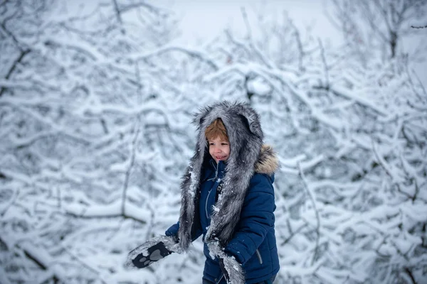 Invierno Niños y naturaleza. Lindo niño en árboles del parque de invierno cubiertos de nieve. Retrato al aire libre de lindo bebé en frío soleado invierno en el parque . — Foto de Stock