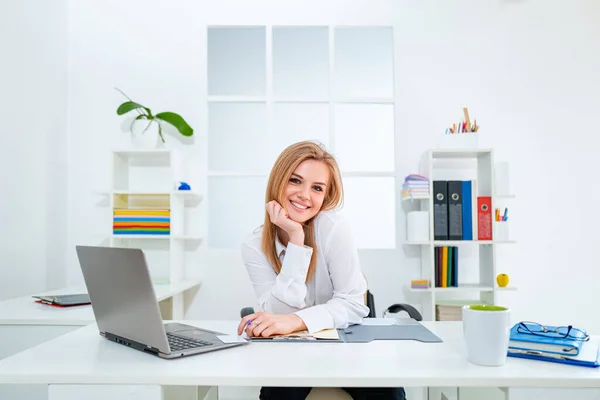 Junge lächelnde Geschäftsfrau im weißen modernen Büro. Schönheit Sekretärin. Schöne junge Frau arbeitet mit Laptop im Büro. — Stockfoto