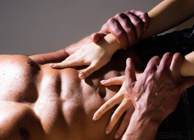 Seksi, kaslı, çıplak bir adam ve çıplak bir kadının elleri. Kadın elleri seksi bir erkeğin gövdesinde. Kadınların elleri, çıplak kaslı erkekleri kucaklıyor. Erkek vücudunda kadın eli..