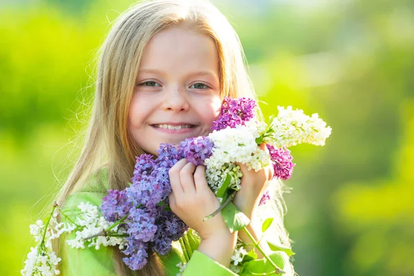 春の庭の女の子。満開の庭で面白い女の子。ライラックの花束を持つ10代の女の子。幸せな笑顔ティーン女の子とともに春の花. — ストック写真