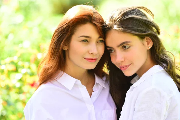 Flickpar tillbringar tid utanför tillsammans. Glada kvinnor i en park på grön våren bakgrund. — Stockfoto