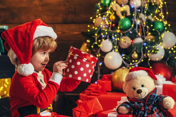 Criança feliz com presente de Natal. Miúdos do Ano Novo. Criança bonito alegre abrindo um presente de Natal. Criança de Natal segurando uma caixa de presente vermelha. Férias de celebração de Natal . — Fotografia de Stock