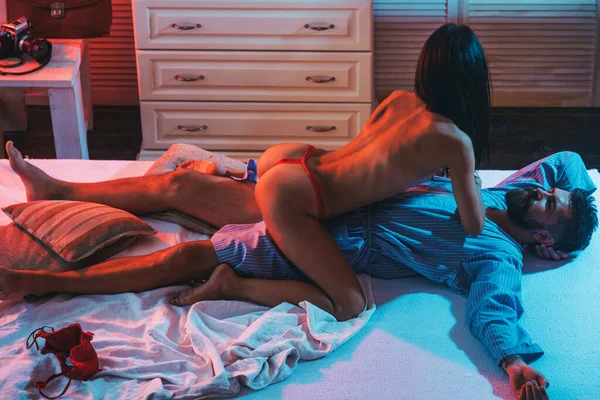 Seksi çiftin ön sevişme ve aşk oyunları. Kırmızı iç çamaşırlı seksi kadın erkek arkadaşına yalan söylüyor. Yatakta ön sevişme oyunu. Aşık seksi çıplak kadın vücudu bir erkekle oynaşıyor..