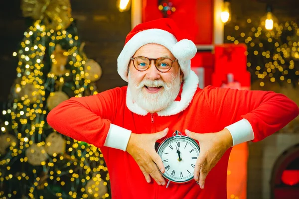 Şükran Günü ve Noel. Noel Baba, Noel ağacı geçmişine karşı alarmlı saat tutuyor. Yeni yıl ve Noel zamanı. Noel Baba evde.. — Stok fotoğraf