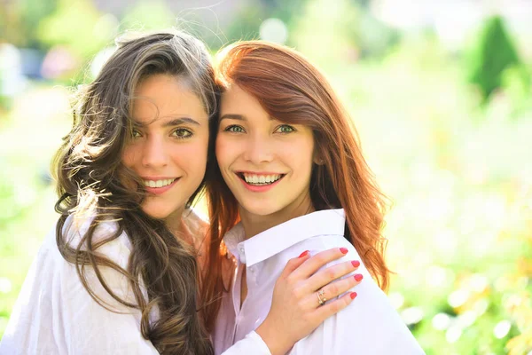 Amigas rindo e abraçando ao ar livre. Duas mulheres estão abraçadas no campo verde. Abraçar conceito . — Fotografia de Stock