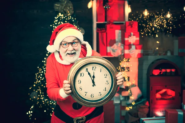 Der Weihnachtsmann mit echtem Bart hält die Uhr. Der lächelnde Weihnachtsmann zeigt den Wecker mit fünf Minuten vor zwölf. Erntedankfest und Weihnachten. — Stockfoto