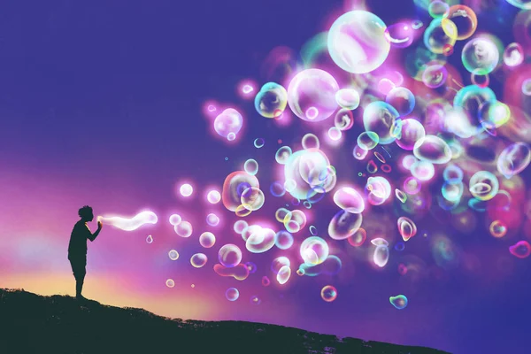 Young man blowing glowing soap bubbles — Stock Photo, Image