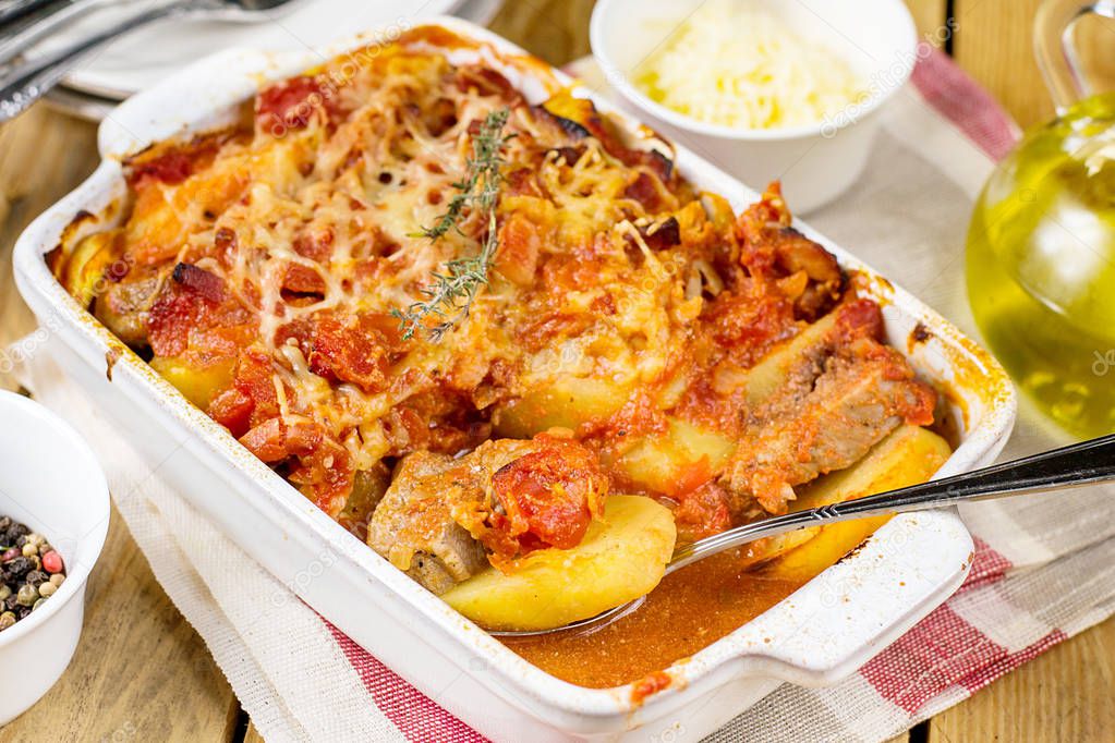 Baked potato gratin with pork meat and tomatoes