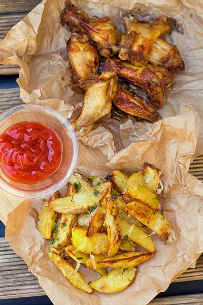 Batatas fritas assadas com asas de frango e baquetas — Fotografia de Stock