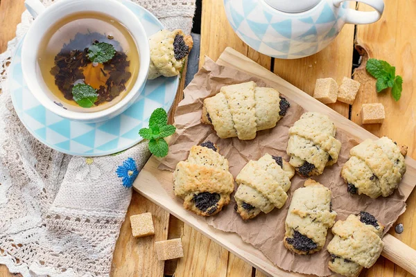 Dulce torta de masa cruasanes rollos con semillas de amapola y te —  Fotos de Stock