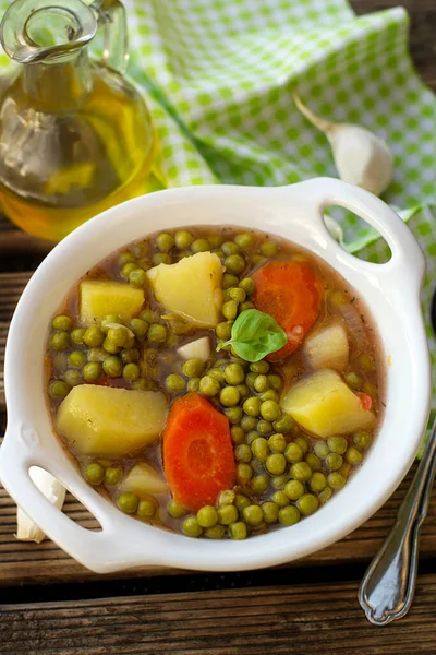 Traditional greek stew with green peas, carrots and tomatoes