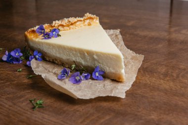 Kağıt üzerinde New York peynirli keki. Dekorasyon mavi çiçekleri. Yakın plan..